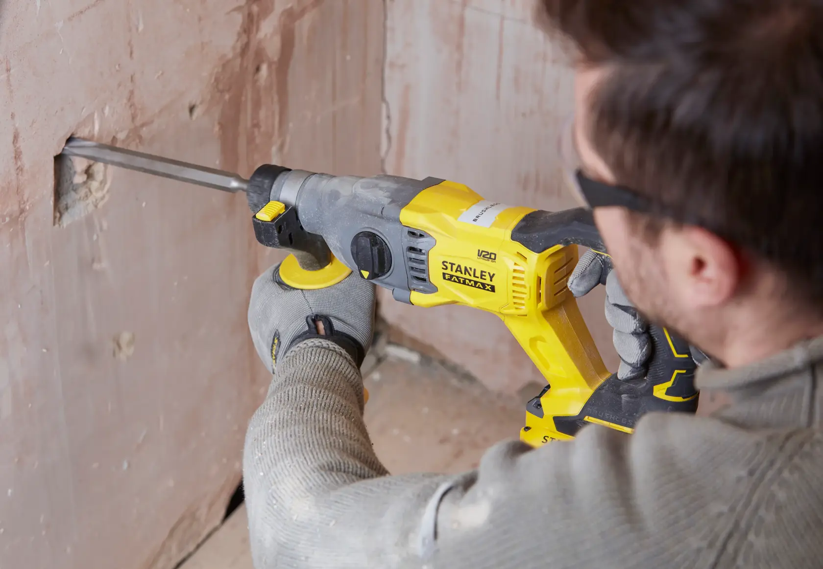 Photo of a person using a STANLEY SFMCH900B rotary hammer drill on a wall.