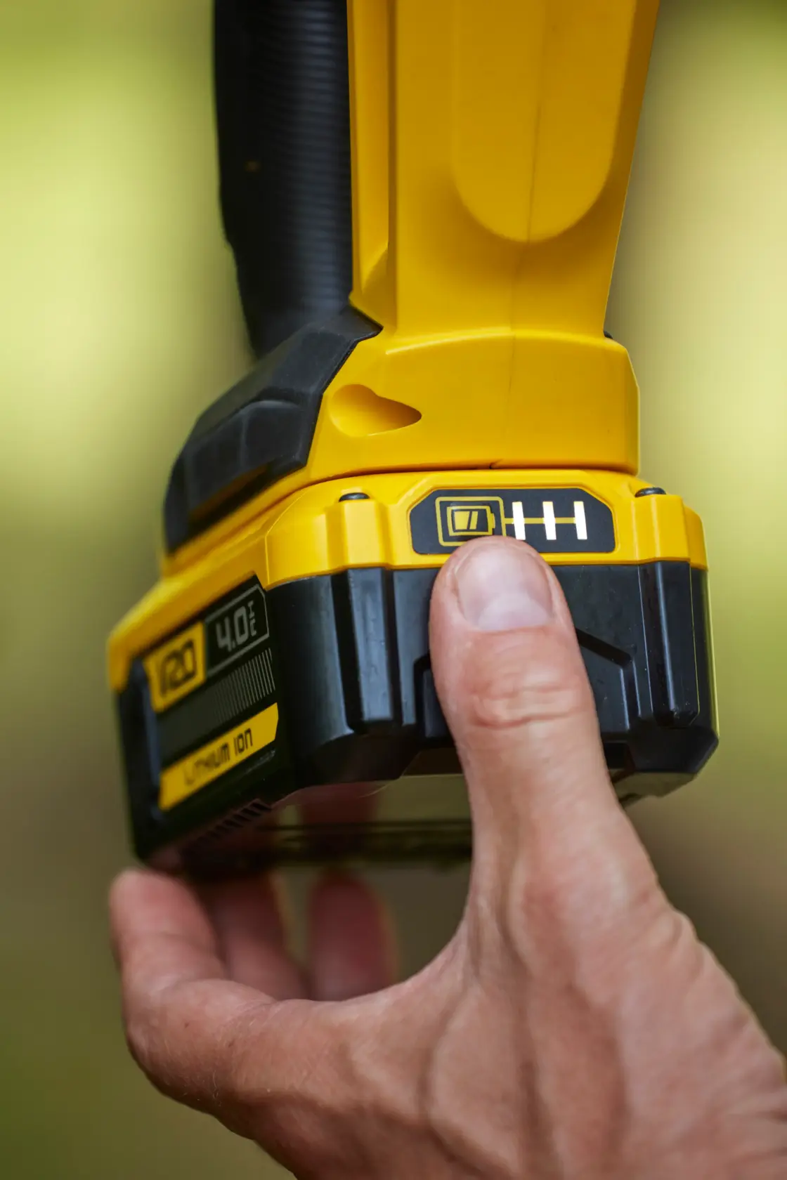 STANLEY SFMCHT855B yellow cordless tool battery being pressed, close-up photography.