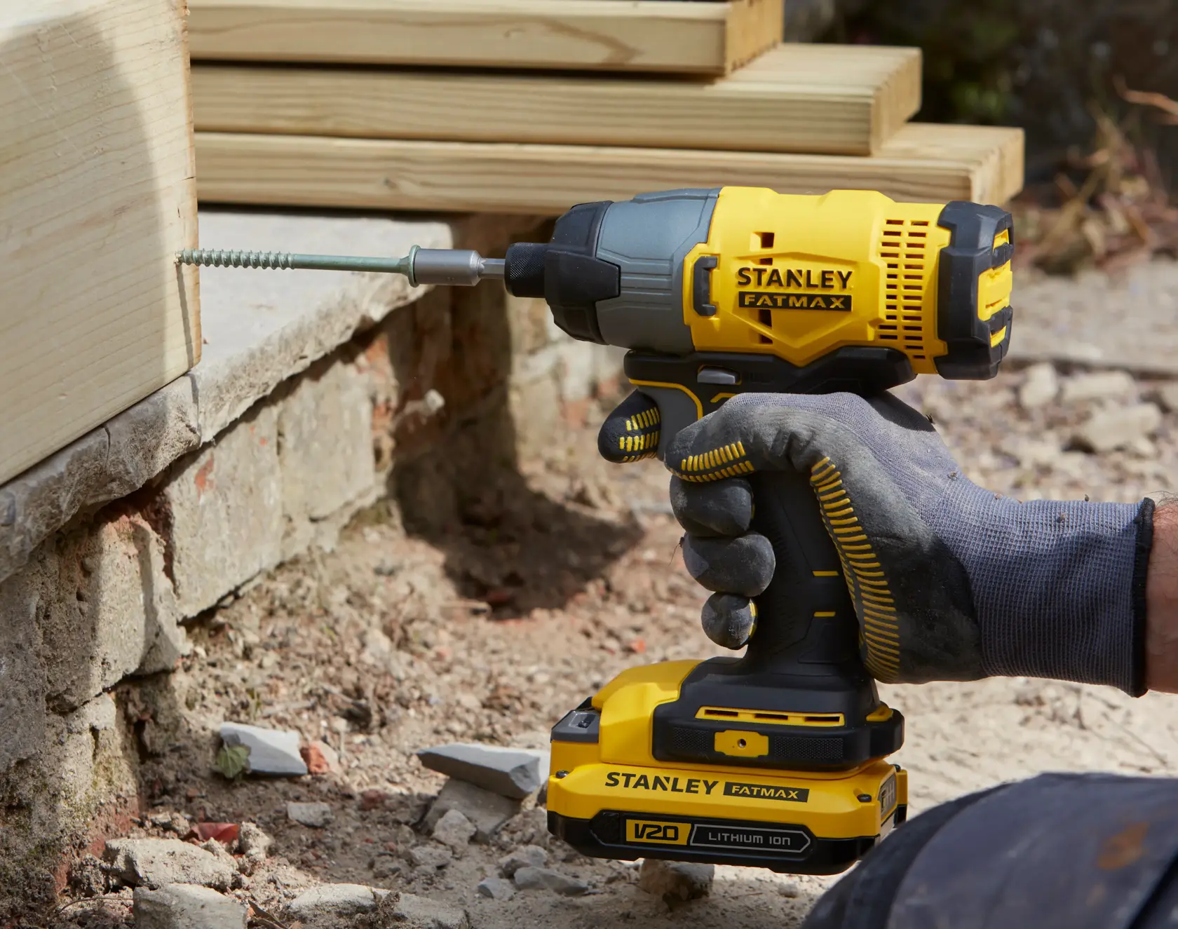 STANLEY SFMCK470D2 impact driver being used to drive a screw into wood, close-up view outdoors.