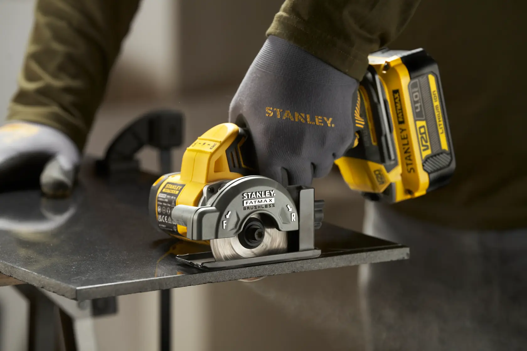 STANLEY SFMCM300B compact circular saw in use, cutting a metal sheet, close-up side angle.