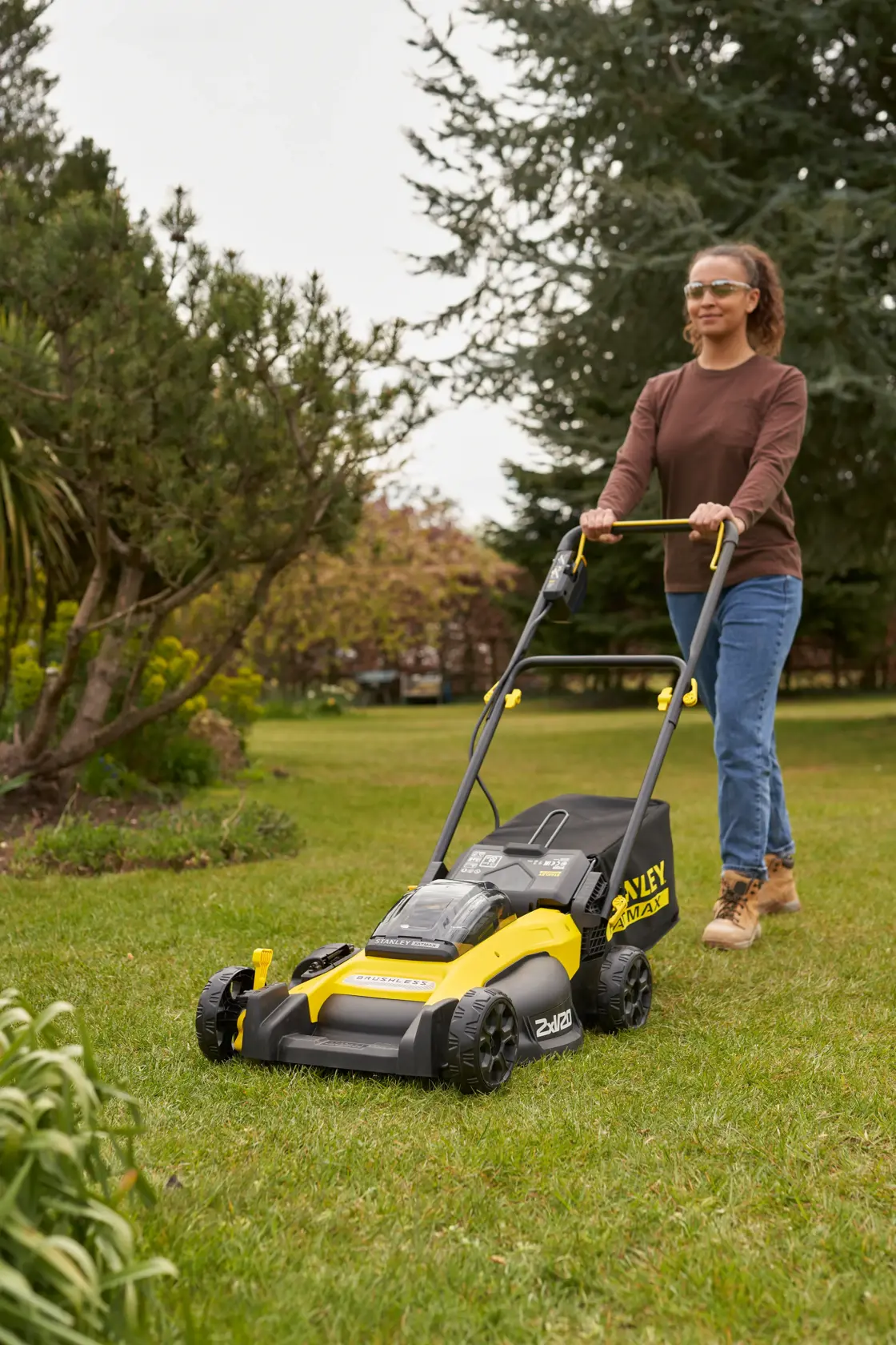 Photo of STANLEY SFMCMW2651M lawn mower in use outdoors on grass by a person, yellow and black design.
