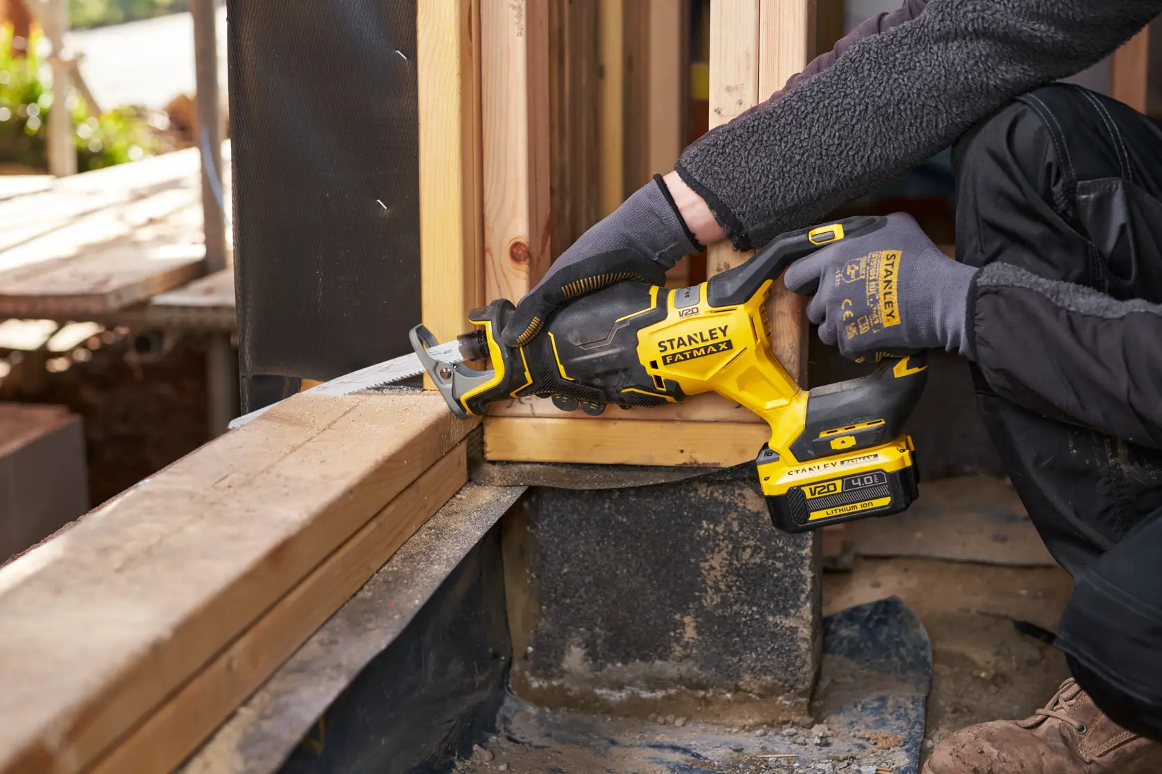 Stanley SFMCS311B-XJ cordless reciprocating saw cutting wood in construction setting, side angle.