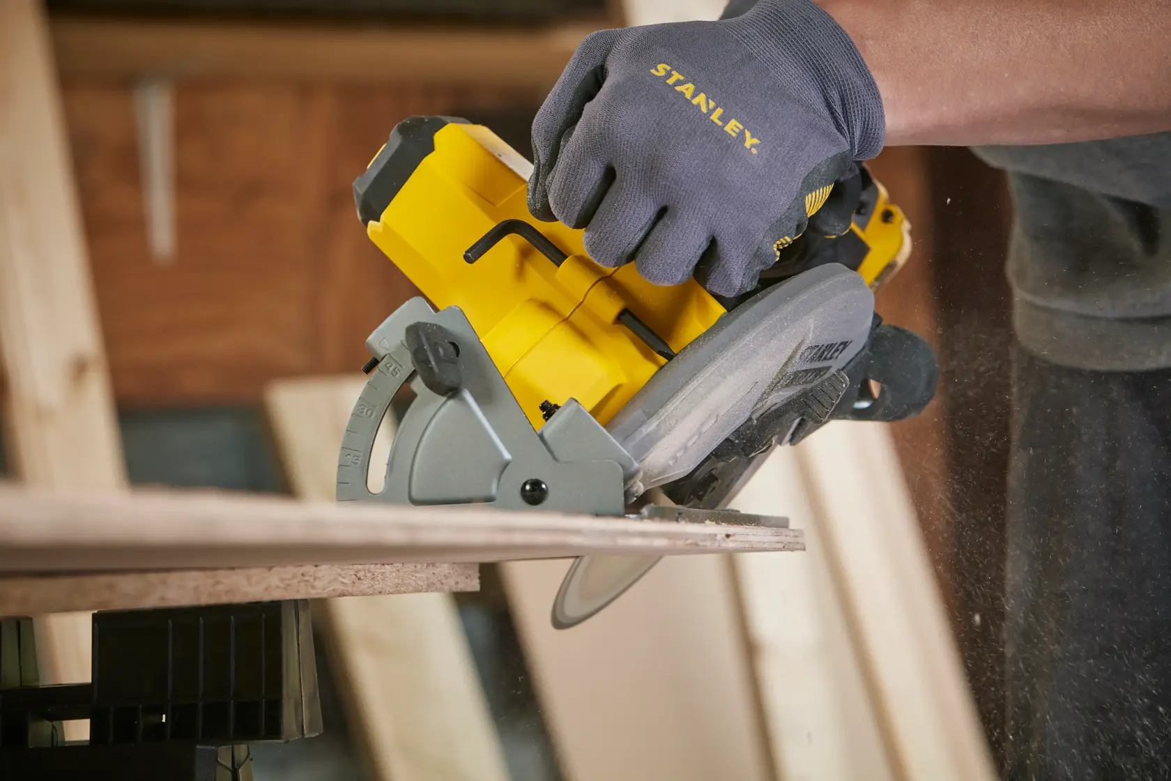Stanley SFMCS500M1S cordless circular saw cutting wood, close-up, with worker wearing Stanley gloves.