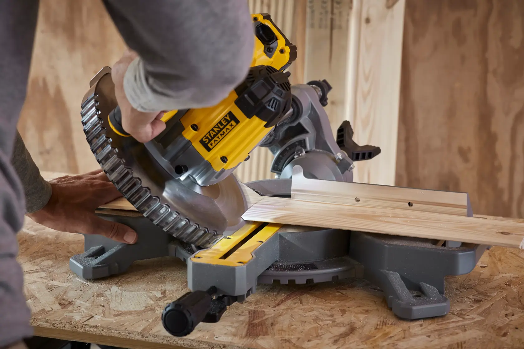 Photo of STANLEY SFMCS701B miter saw cutting wood on workbench, close-up action shot.