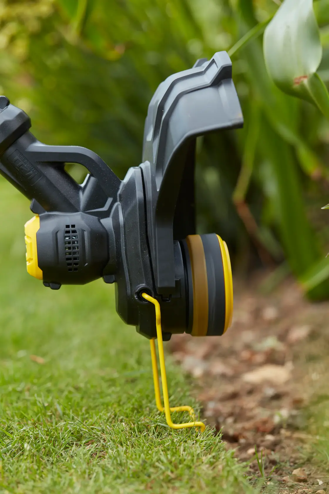 STANLEY SFMCST933B grass trimmer close-up photo showing the cutting head and yellow guard during lawn edging.