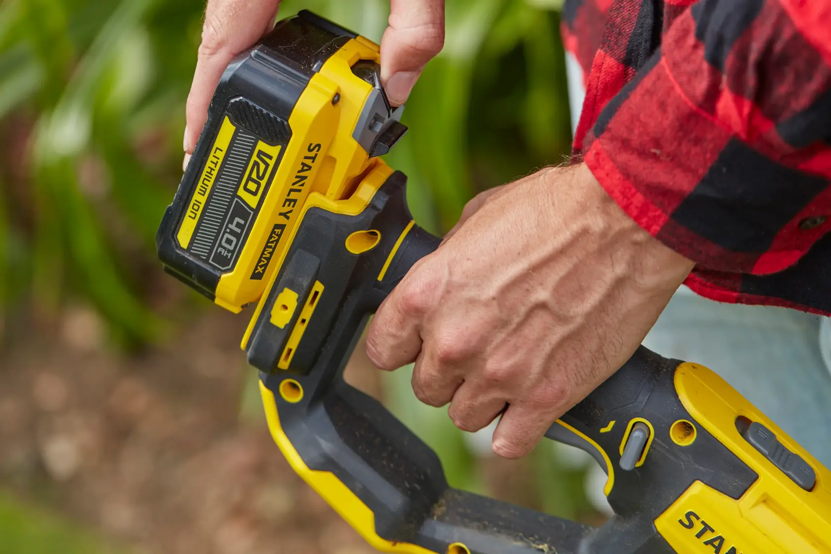 Photo of STANLEY SFMCST933M1 V20 Lithium-Ion tool, close-up of battery being attached outdoors.