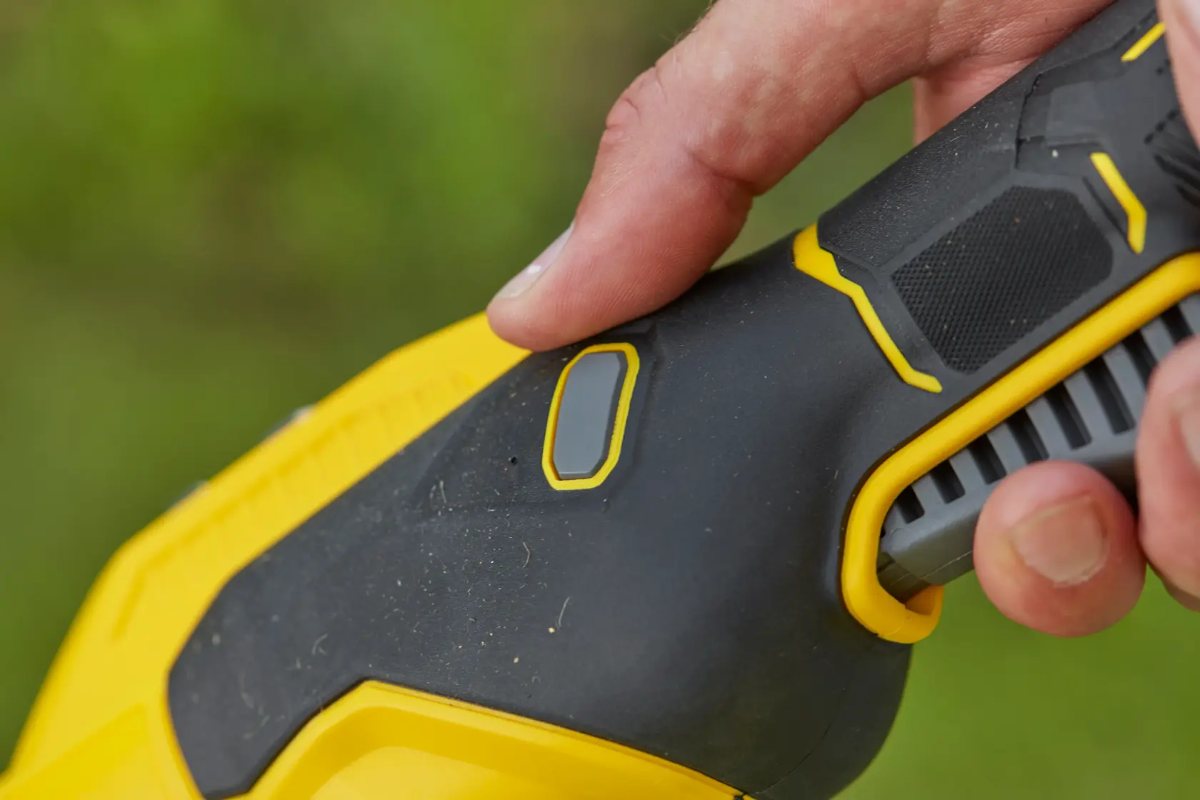 STANLEY SFMCSTB933B power tool handle in black and yellow with finger pressing the button, close-up photo.