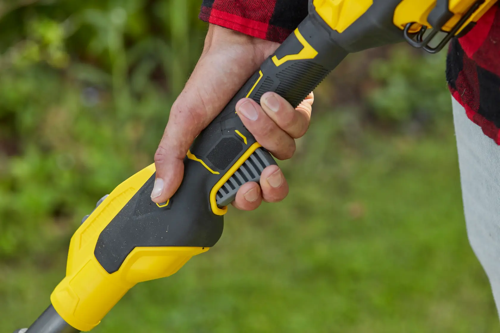 STANLEY SFMCSTB933M string trimmer handle close-up held by hand, black and yellow finish.