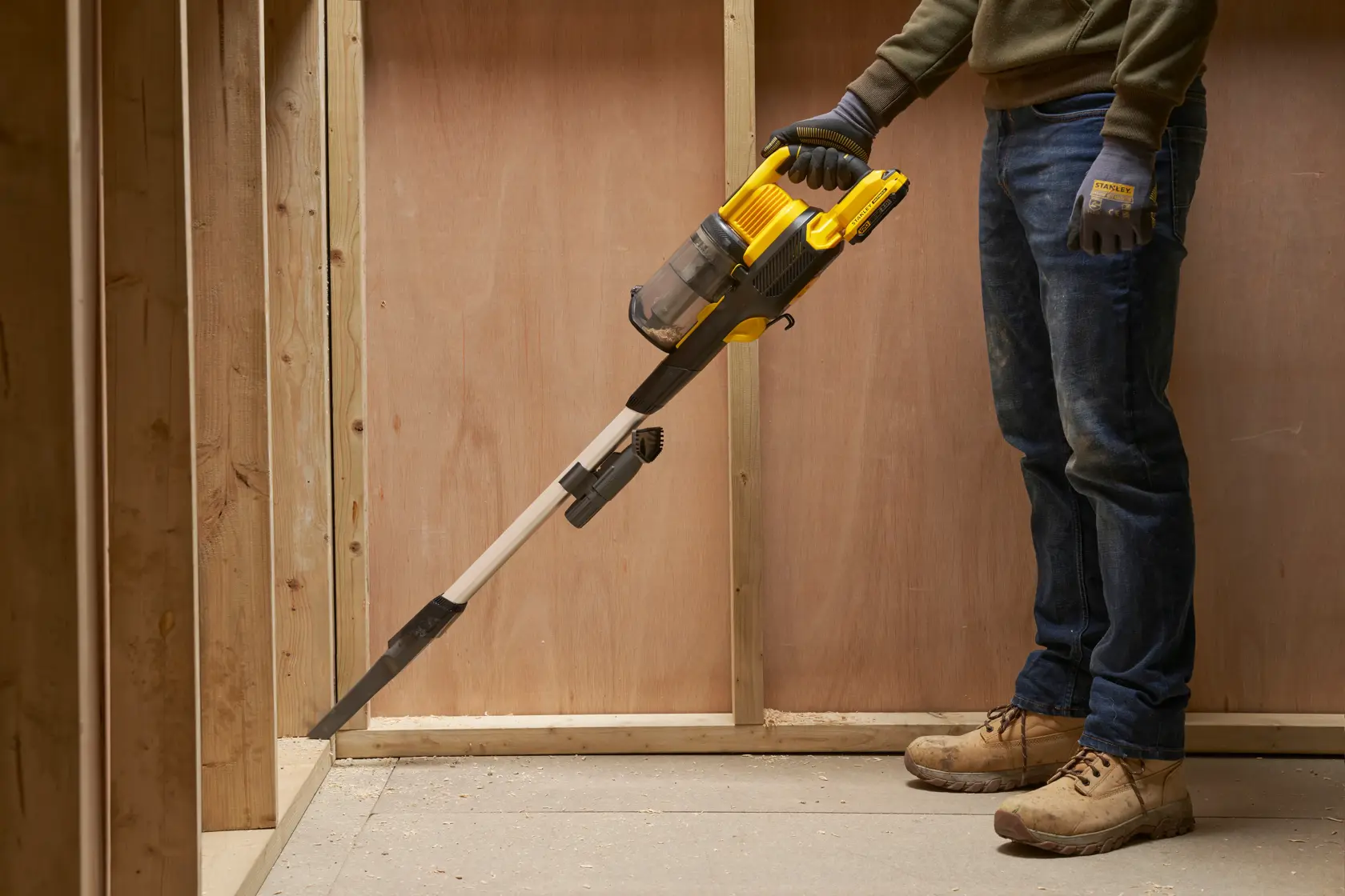 STANLEY SFMCVS001D1 handheld vacuum cleaner in use, yellow and black, cleaning a construction corner.