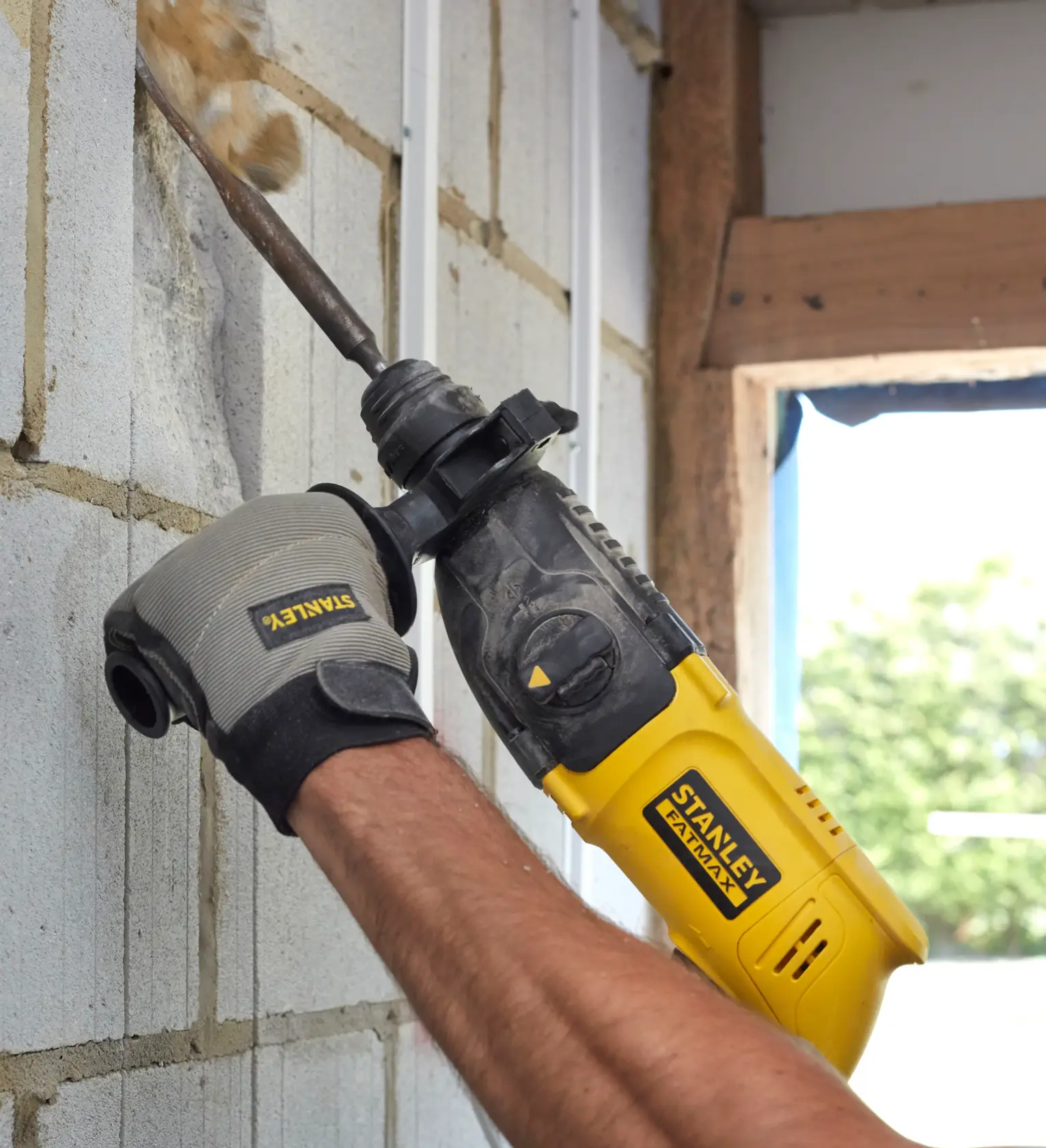 Stanley SFMEH200K hammer drill being used on a masonry wall, close-up view.