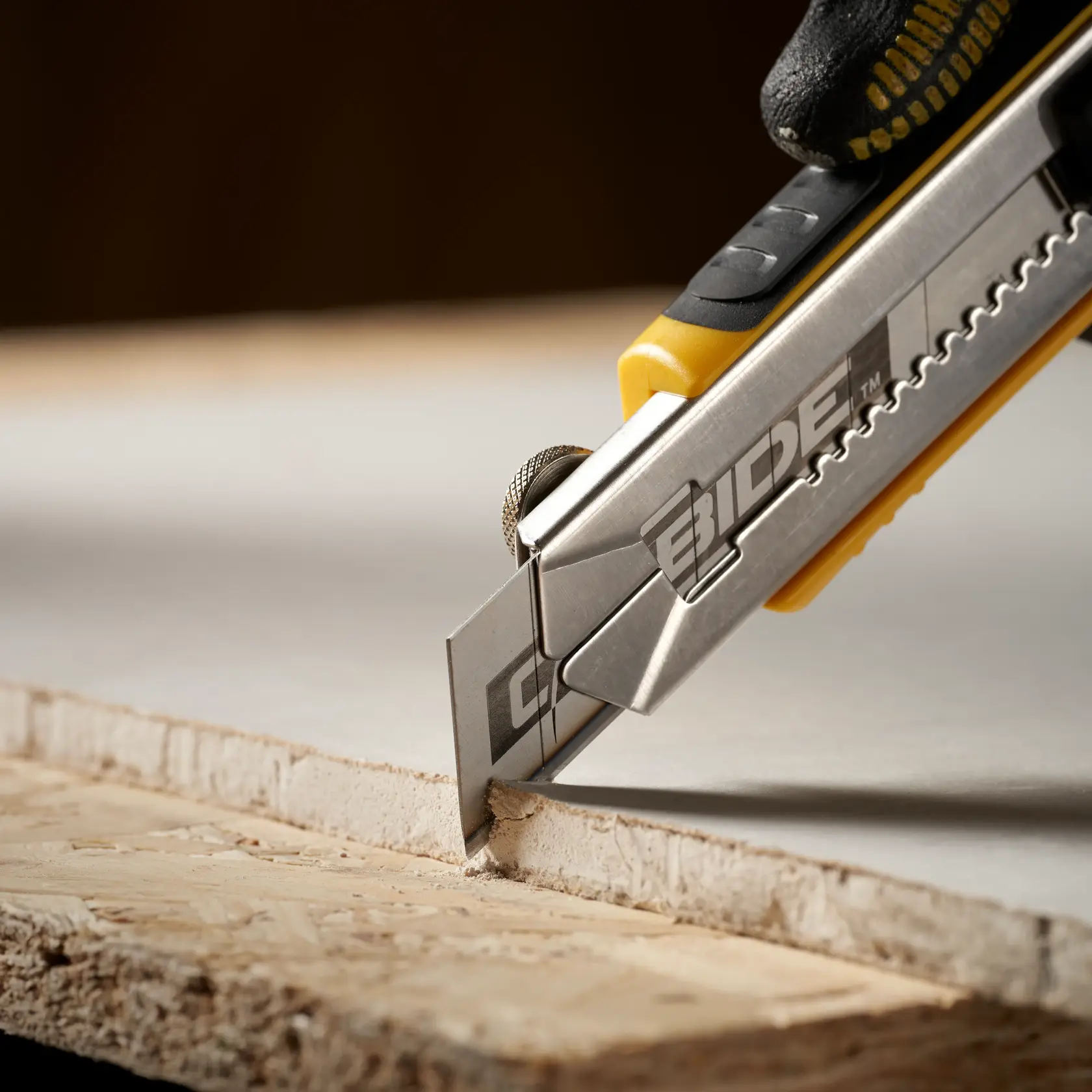 STANLEY STHT0-11825 utility knife cutting drywall, close-up, with silver blade and yellow handle.