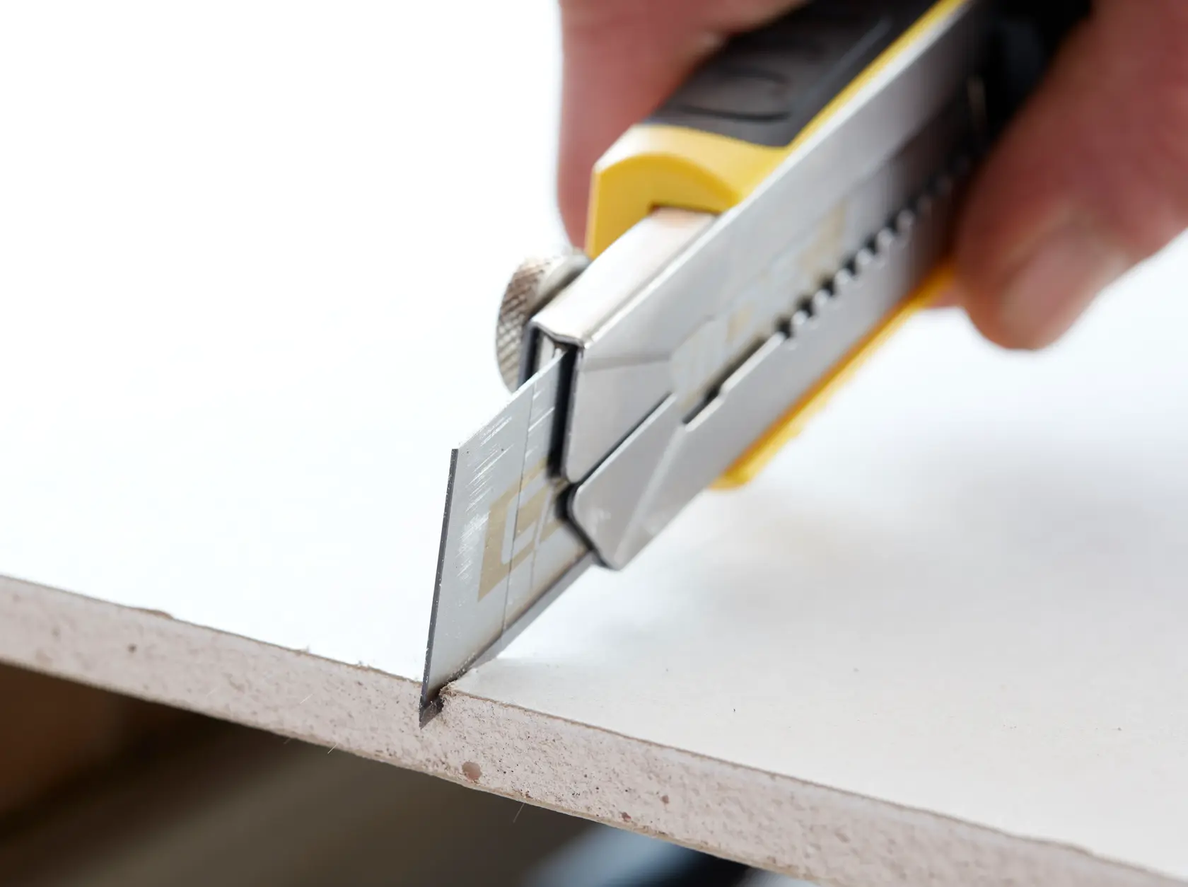STANLEY STHT0-11825 utility knife cutting drywall, close-up showing blade and handle.