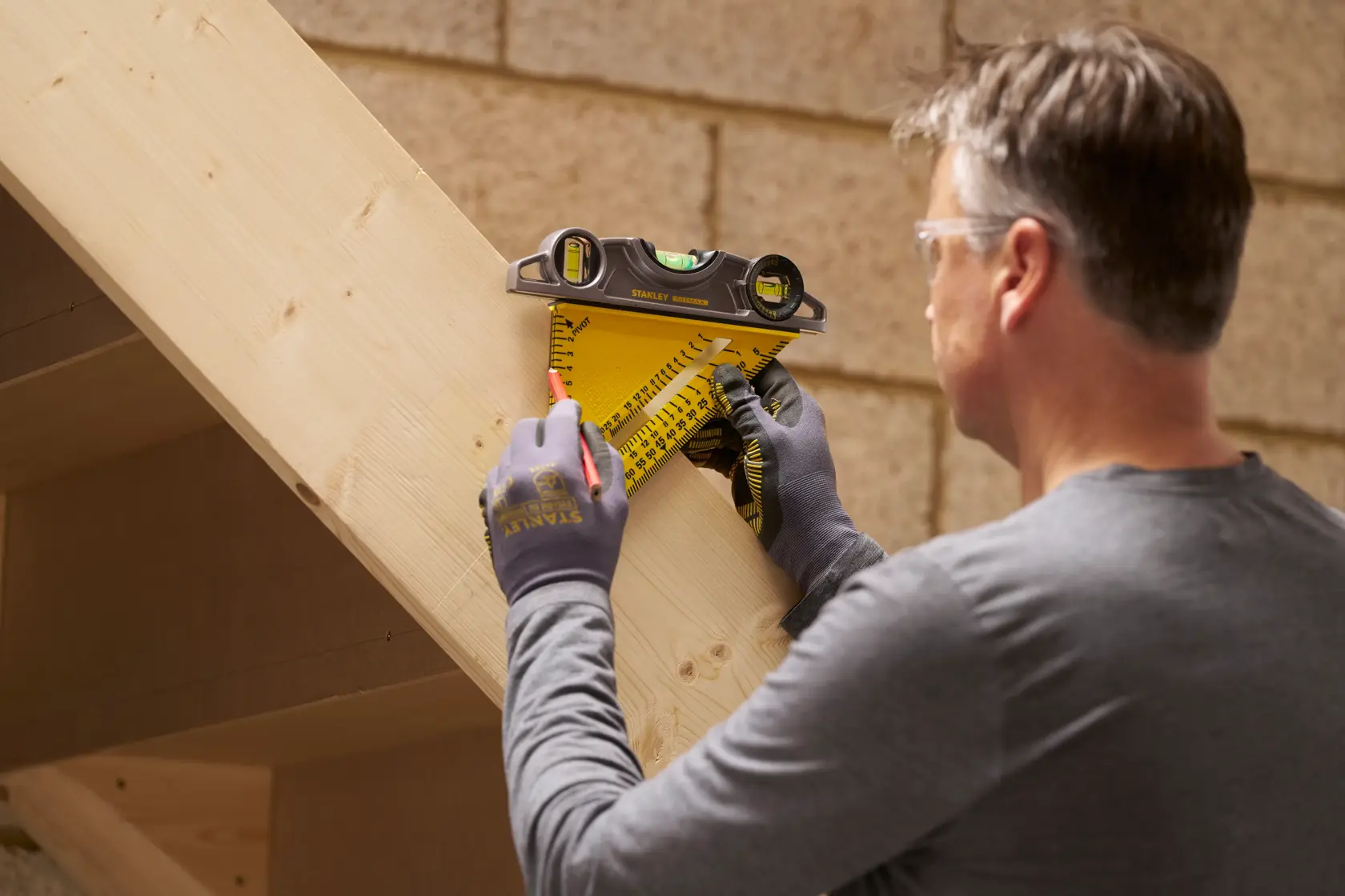 STANLEY STHT46012-0 rafter square with level used by person marking measurements on wooden beam.