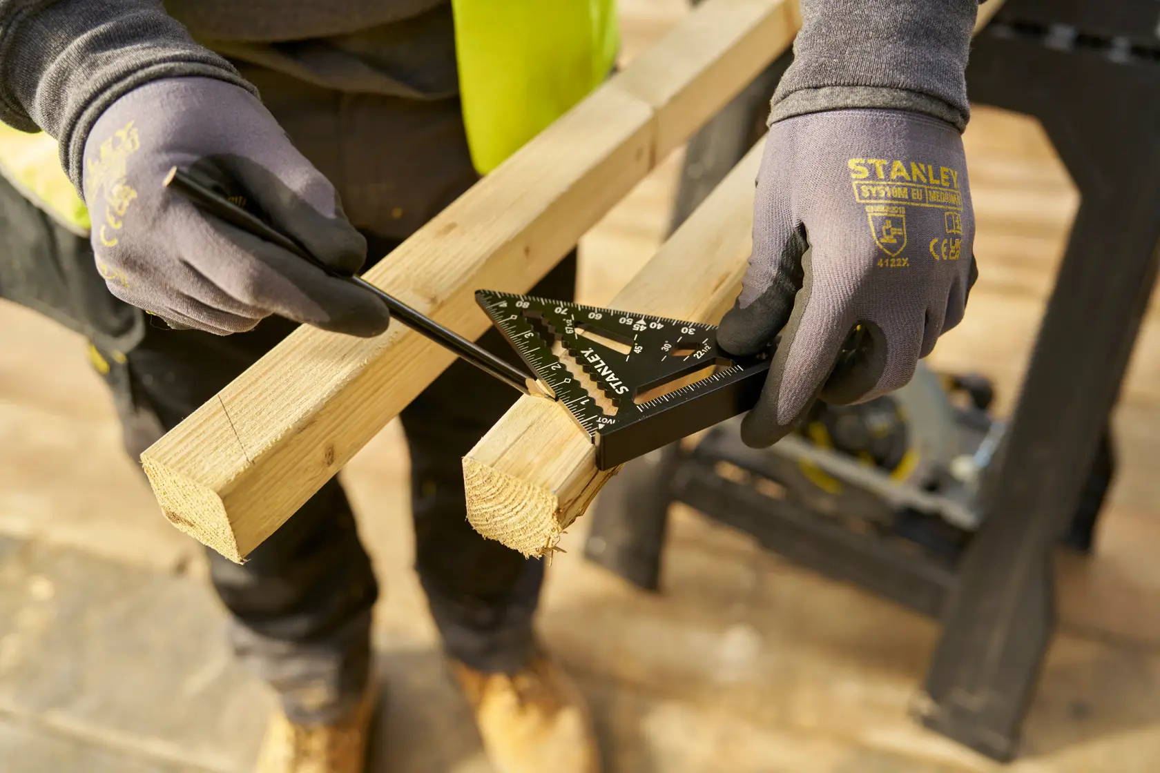 Photo of STANLEY STHT46103-0 layout square marking a wooden beam, gloved hands holding tool and pencil.